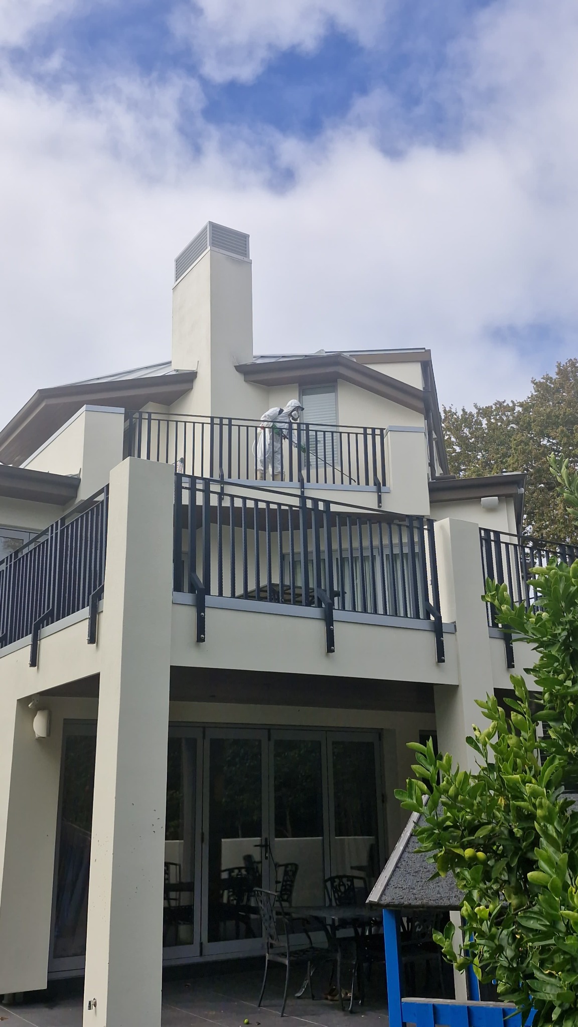 Technician applying outdoor wood cockroach treatment at a residential property